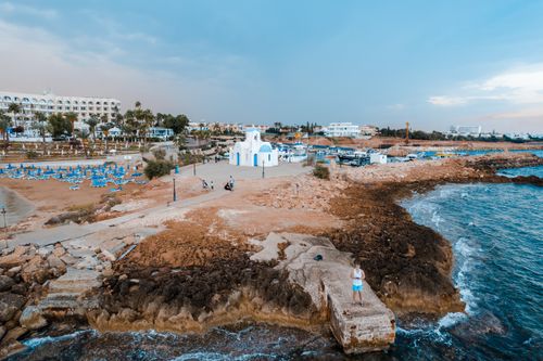 Free Aerial shot of a picturesque church by the seaside in Pernera, Cyprus, capturing the serene coastline and vibrant tourist area. Stock Photo