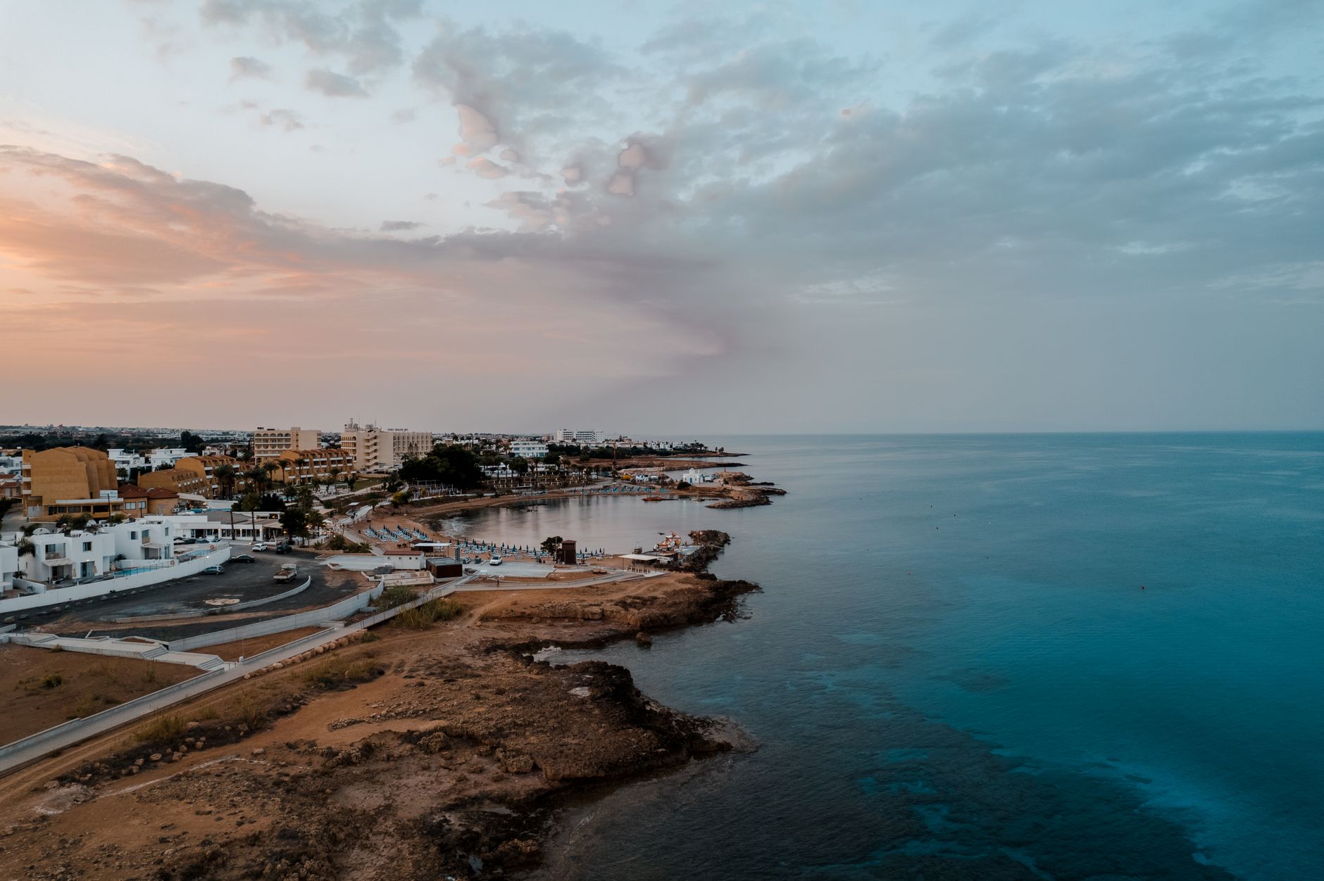 A stunning aerial shot of Protaras, Cyprus coastline with calm seas and a colorful sunset sky. — photo by Ollie Craig / Pexels