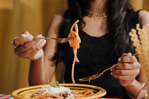 A Female Hands Holding Forks With a Pasta one one of Them 