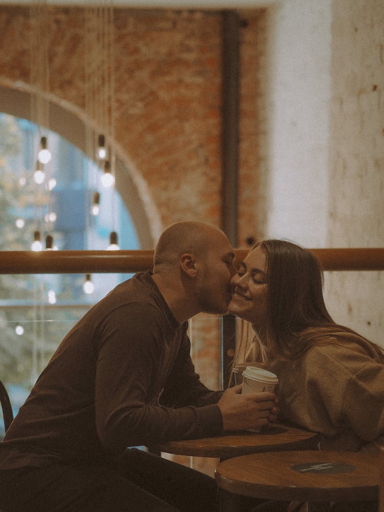 Man Kissing Woman In Cafe