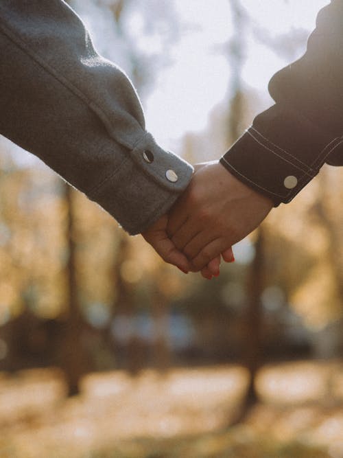 A Sweet Couple Wearing Long Sleeves Holding Each Others Hand