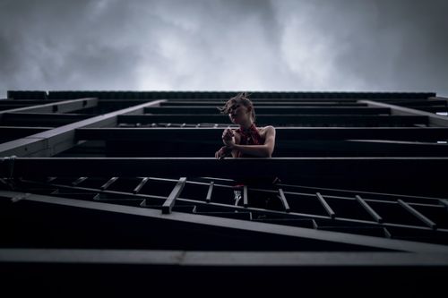 Free A person stands on a balcony, silhouetted against a dramatic cloudy sky, creating a moody atmosphere. Stock Photo