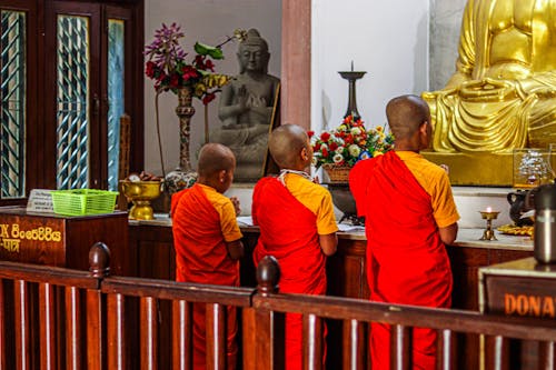 Three Boys Praying In Front of a Buddha in a Temple