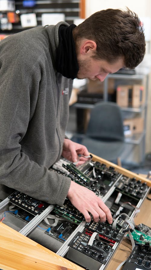 Man in Gray Sweater Fixing Audio Mixer