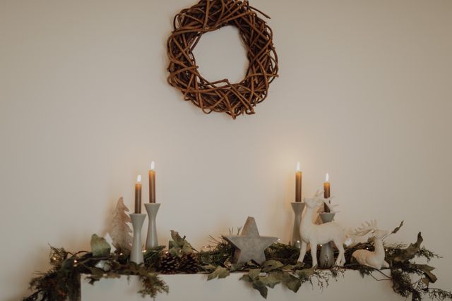 Candles, a woven wreath and dried greenery on a pale mantel — photo by Doralin Tunas on Pexels