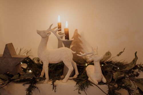 Free Warm candlelit decor featuring deer sculptures and greenery for a festive ambiance. Stock Photo