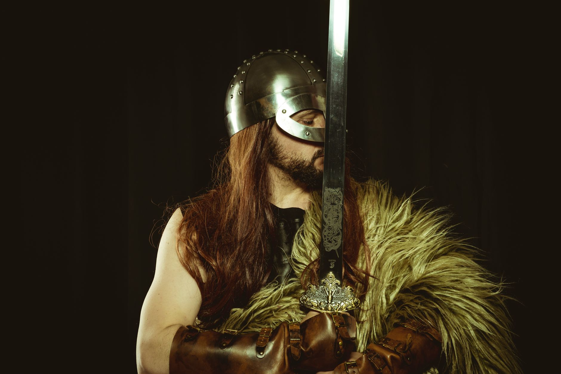 A medieval warrior in full armor, wearing a helmet and holding a large sword.