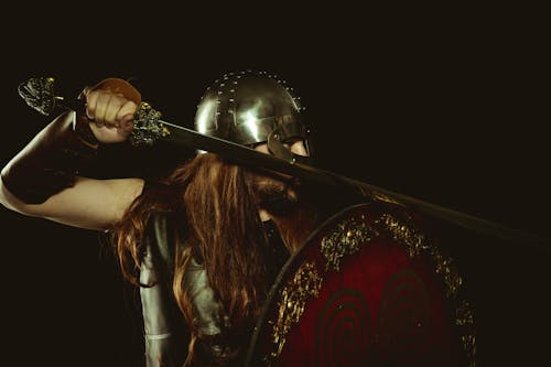Free Man in Viking Warrior Costume Holding Sword and Armor Stock Photo