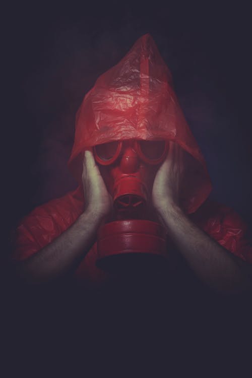 Man in Red Plastic Jacket Wearing Red Gas Mask