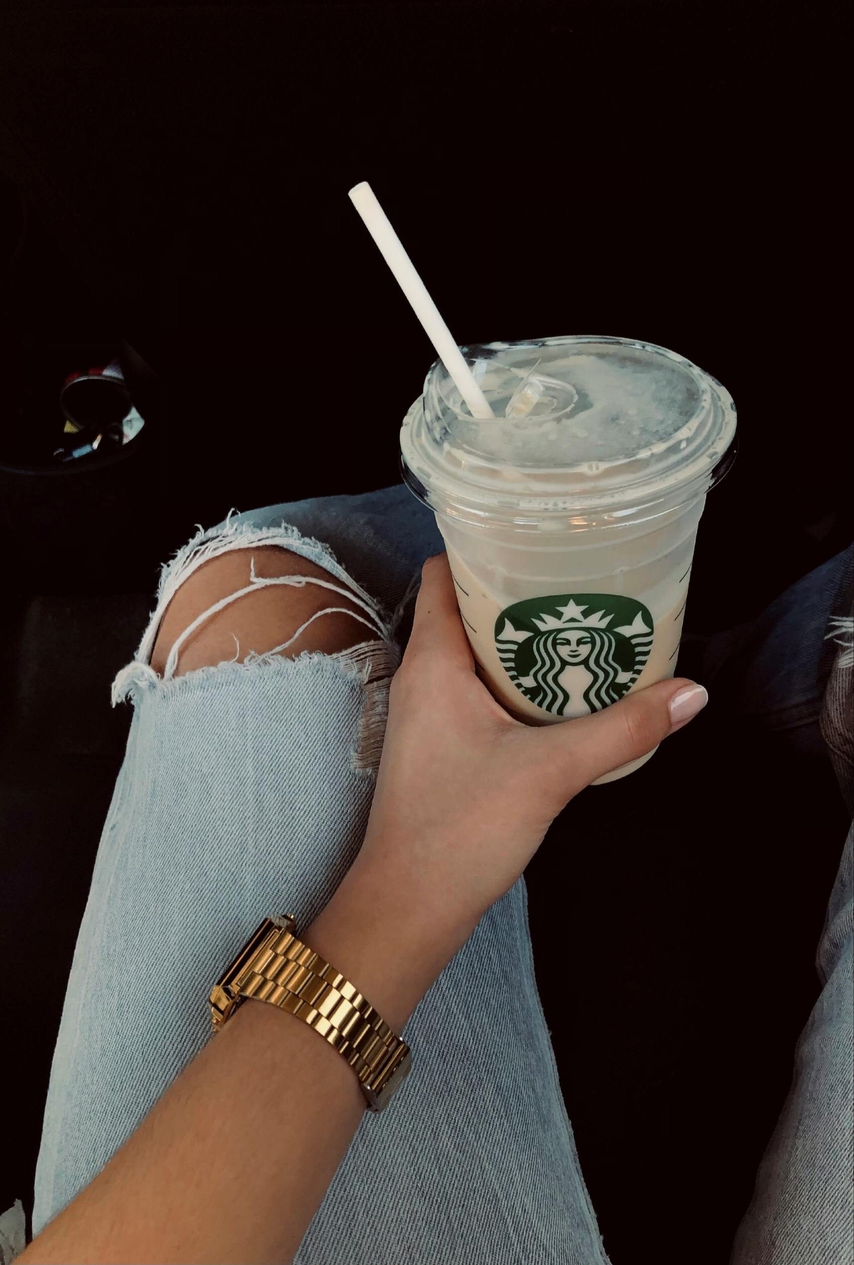 a woman holding a starbucks drink