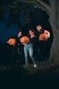 A Group of Women Standing Beside the Tree while Holding Carved Pumpkins