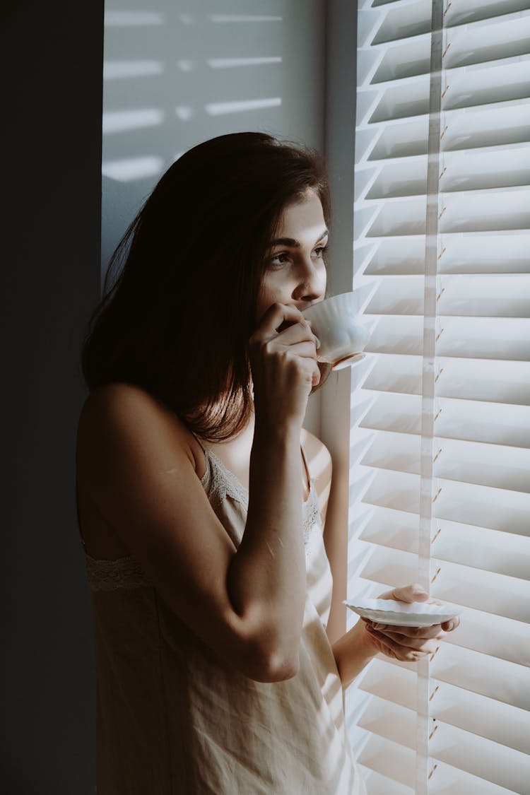 A Woman Drinking Coffee By The Window