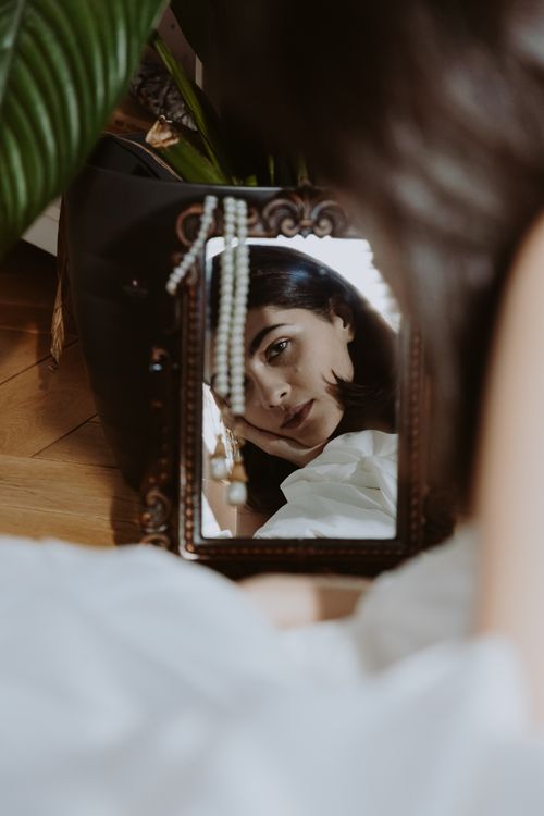 Free Caucasian woman in a vintage mirror, serene indoor setting Stock Photo
