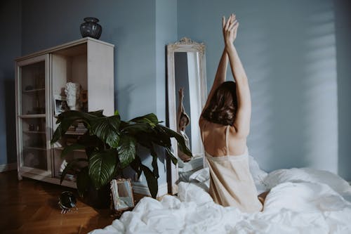 Free Photo of a Woman Raising Her Hands while Looking at the Mirror Stock Photo