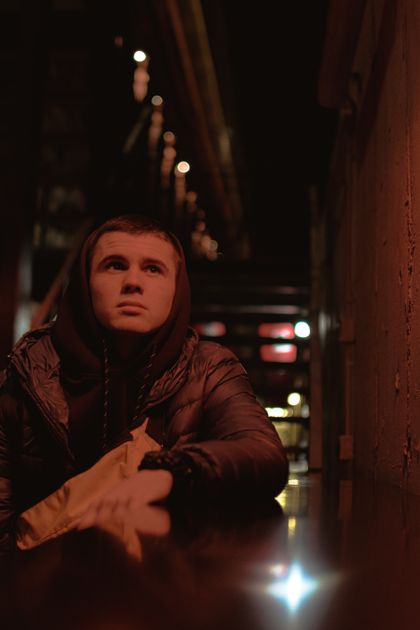 A person in a black hoodie sitting outdoors at night — photo by Denis Nagaytsev on Pexels
