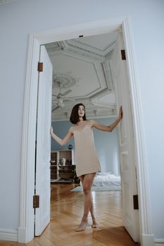 A woman in a stylish dress poses gracefully in an ornate doorway, capturing elegance and style.