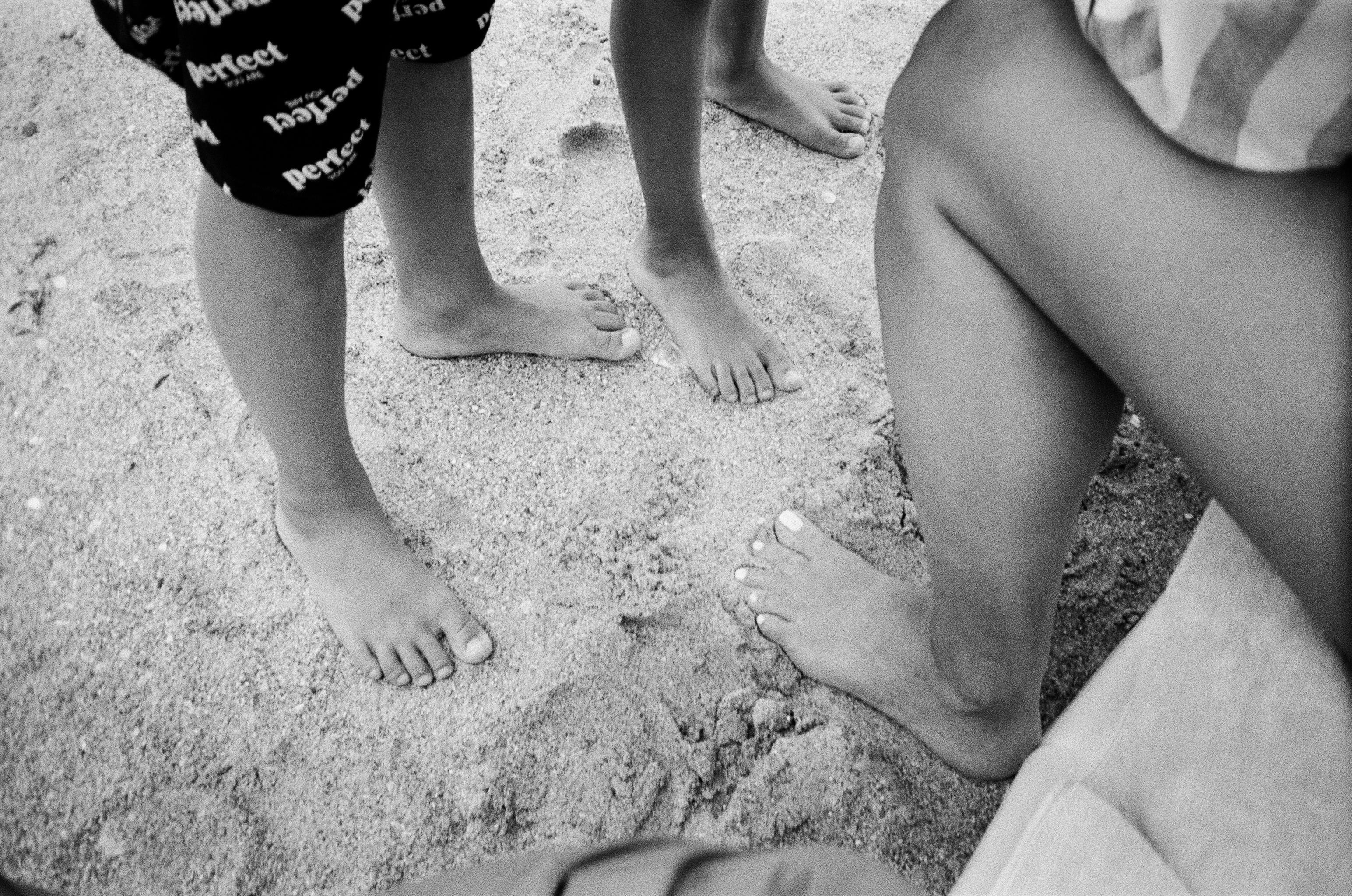 monochrome photo of people s feet on the sand