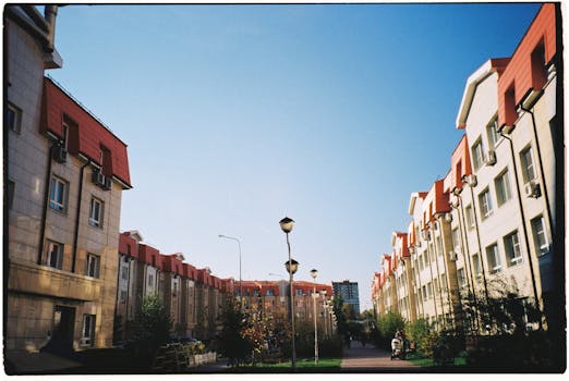 Scenic view of urban architecture with aligned apartment buildings and greenery under a clear blue sky.