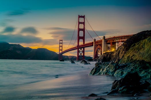 Stunning view of the Golden Gate Bridge at dusk with ocean waves and dramatic sky. by zoe pappas