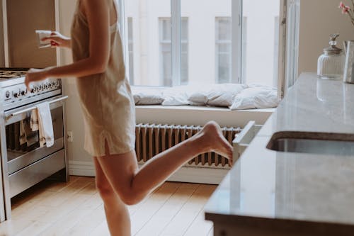 Free Woman in Nightdress Closing Kitchen Drawer with Foot Stock Photo