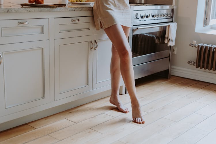 Woman In Nightdress Standing Barefoot In The Kitchen