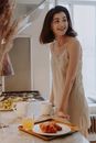Smiling Woman in Nightdress Standing Beside Table With Juice and Croissants