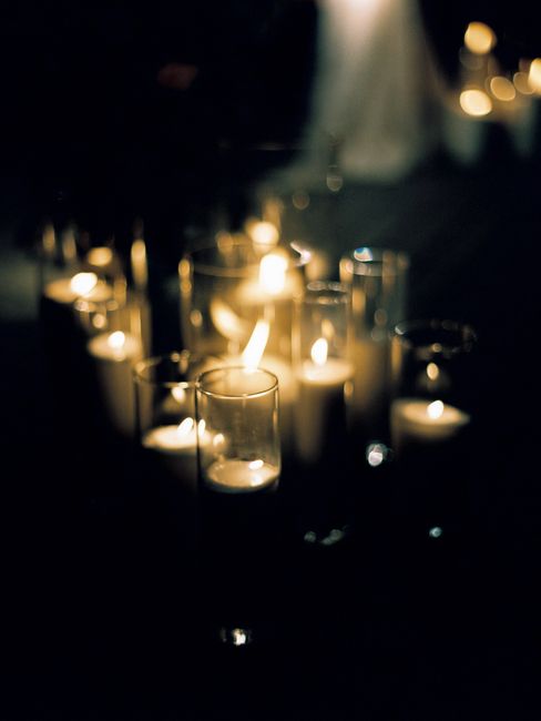 Elegant display of lit candles in glass holders creating a warm, moody ambiance.