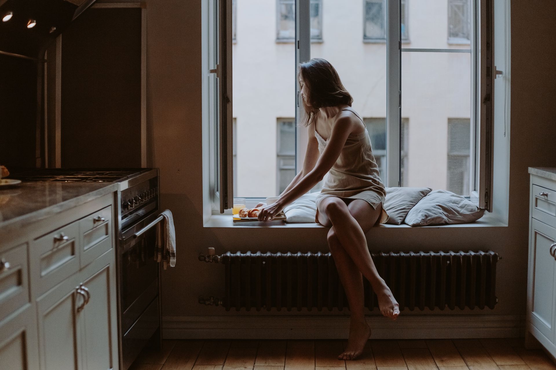 A Woman Sitting on Window Seat Holding a Tray of Food