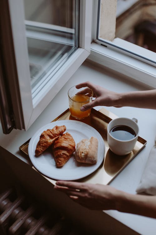 A Croissants on a Ceramic Plate Near the Coffee and a Glass of Juice