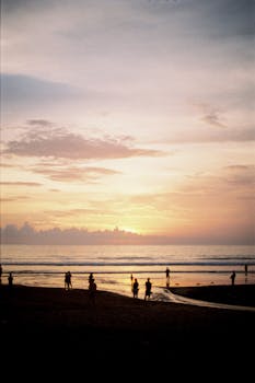 Captivating silhouettes against a moody Bali sunset sky, showcasing serene beach beauty.