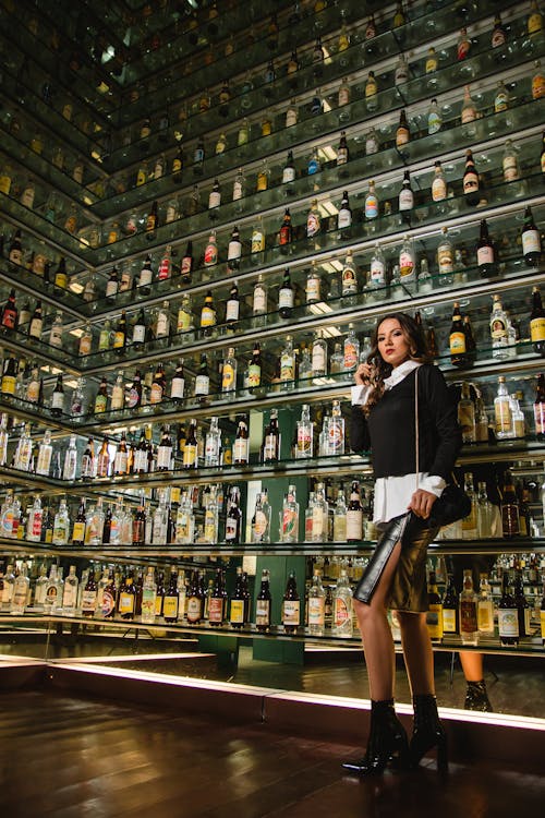 Free Photo of Woman Standing Near Shelves for Liquor Stock Photo