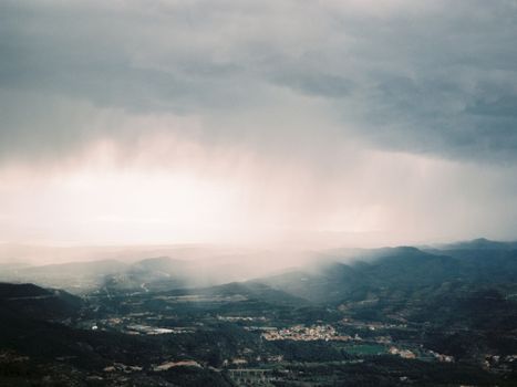 A stunning view of Montserrat valley with dramatic clouds and sun rays breaking through.