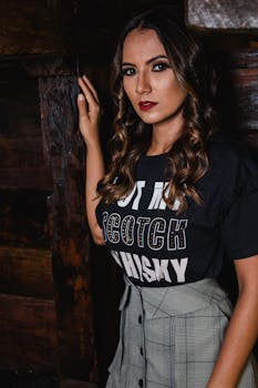 Young woman with curly hair in a fashion photoshoot, wearing bold makeup and stylish attire indoors.