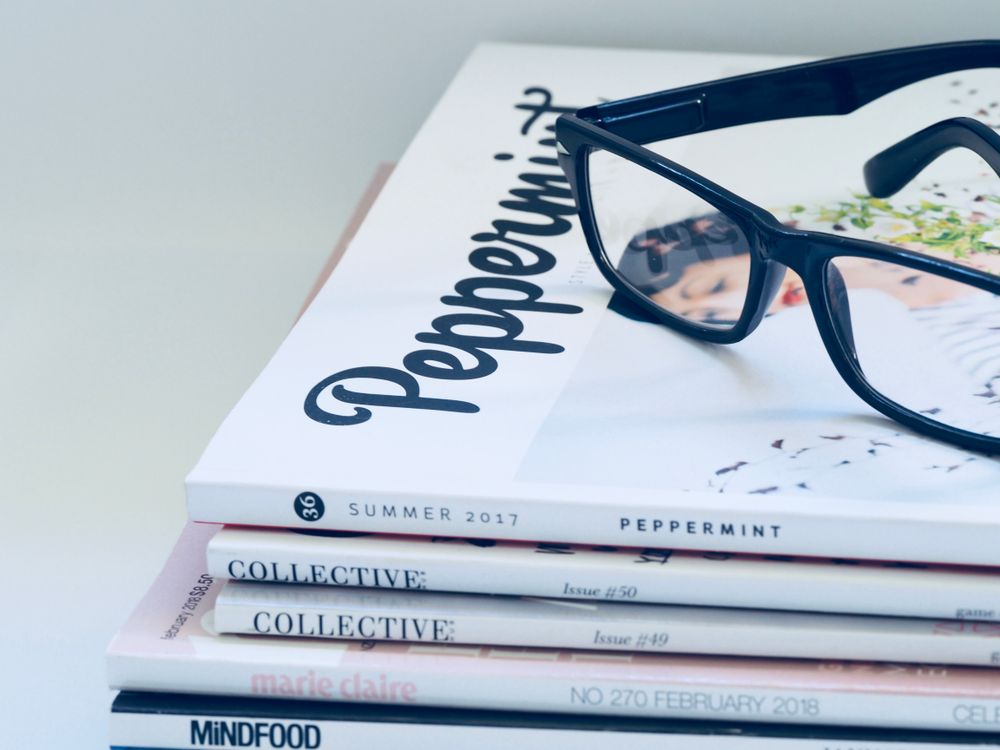 Bril op een stapel mode- en lifestyletijdschriften