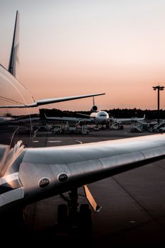 Two airplanes parked on a tarmac during sunset, showing airport operations.