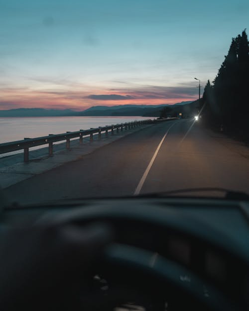 Gray Concrete Road Near Body of Water during Sunset