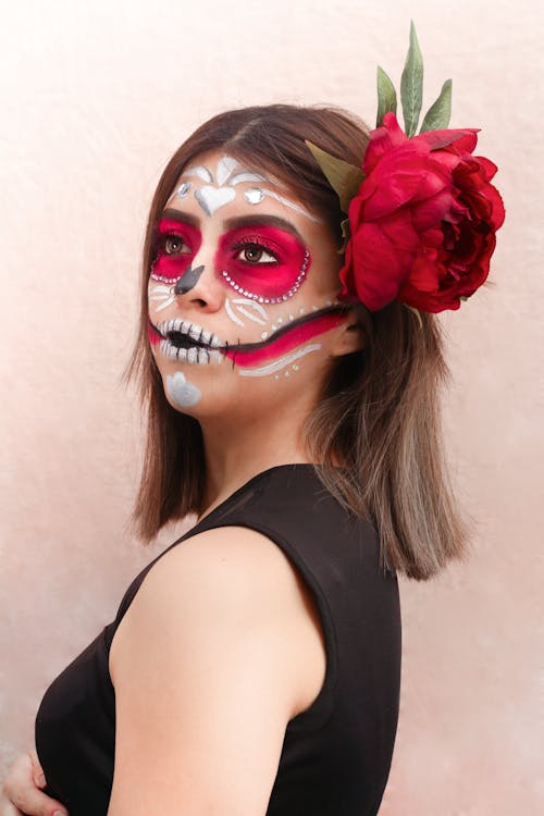 A Woman with a Face Paint Wearing a Red Flower on Her Hair