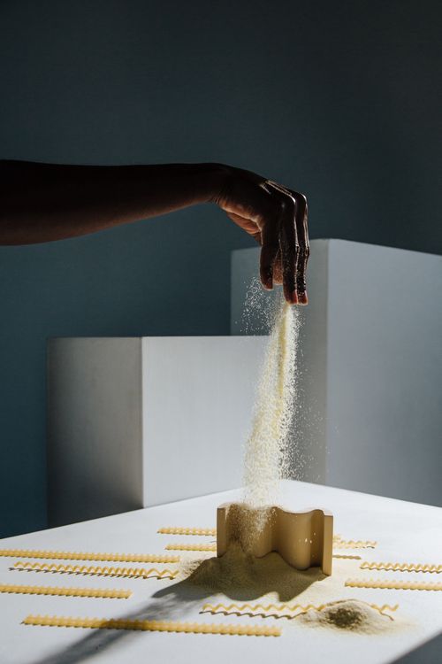 Free Artistic shot of pasta flour flowing through fingers in a studio setting, emphasizing creativity and motion. Stock Photo