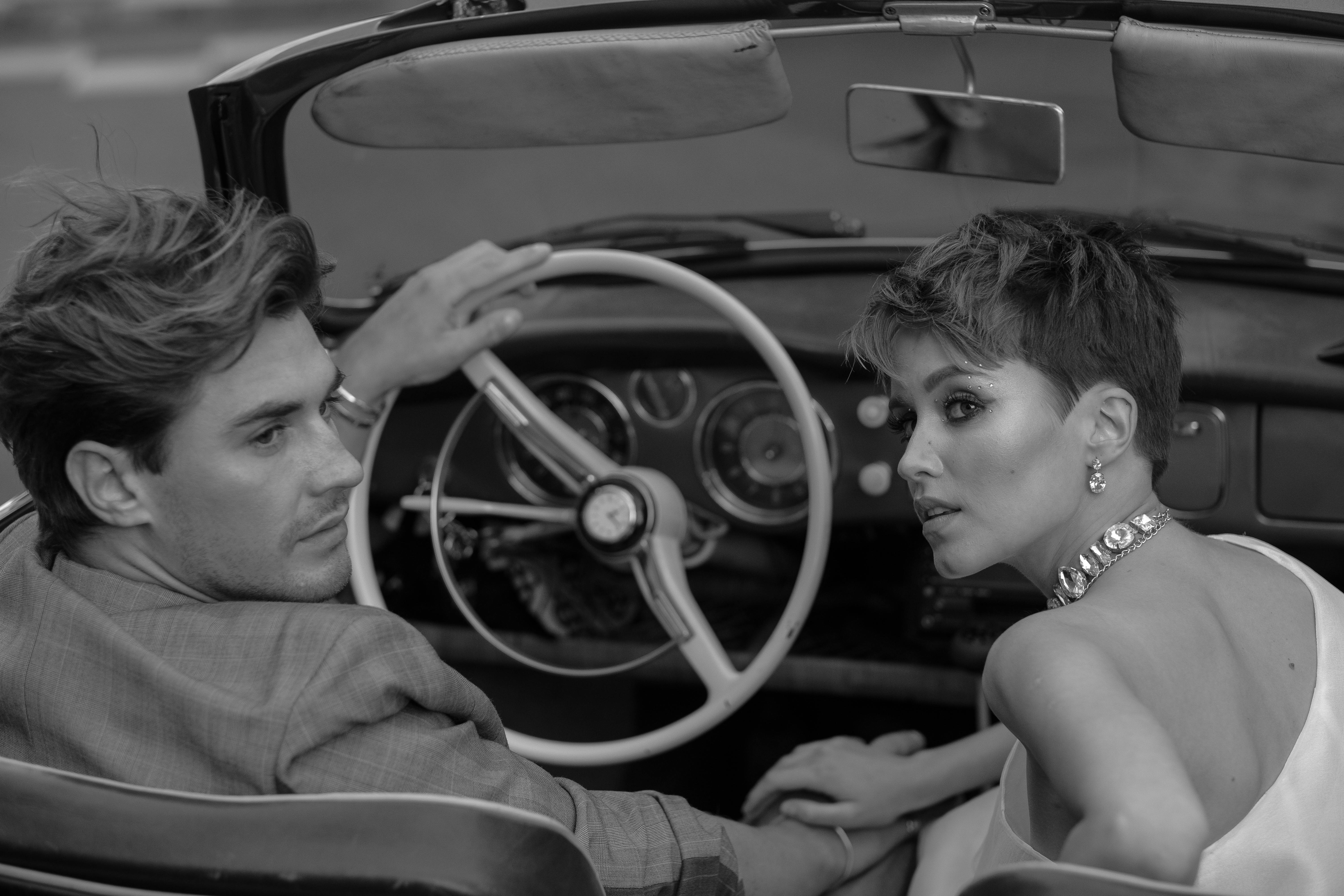 black and white portrait of bride and groom sitting in vintage car