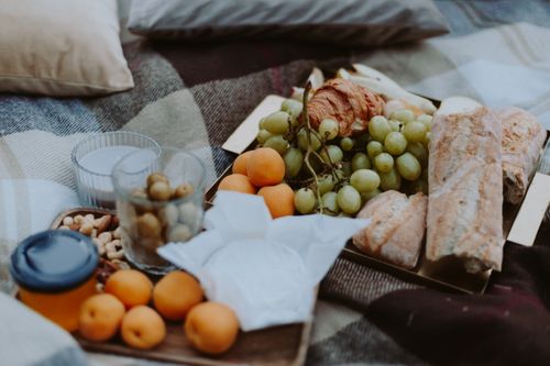 Free Rustic picnic setup with fresh fruits, bread, and snacks on a plaid blanket outdoors. Stock Photo