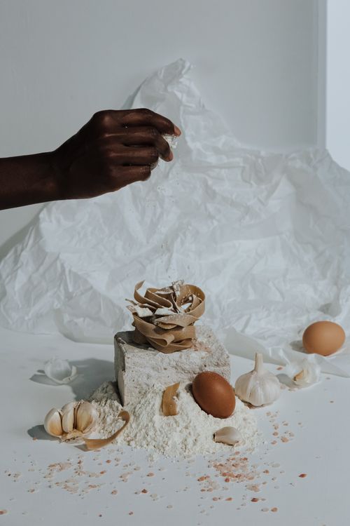 Free Stylized display of cooking ingredients with eggshells, flour, and garlic. Stock Photo