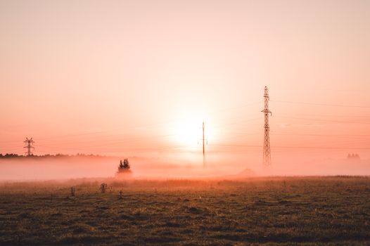 Jak podnieść swoją energię w 5 krokach – praktyczny przewodnik 1 Tranquil sunrise with fog and power lines over a field in Zhukovo, Bashkortostan, Russia.