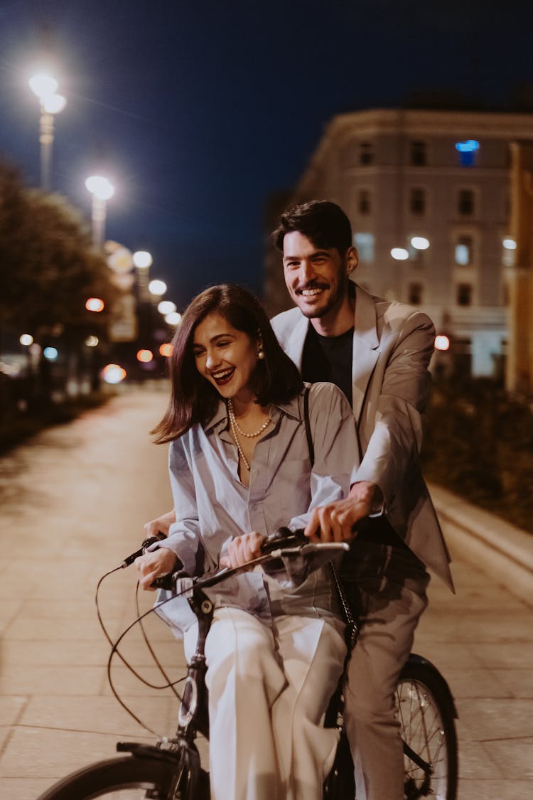 A Couple Riding A Bicycle At Night