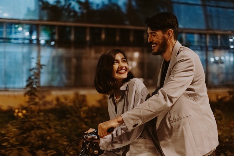 Photo Of A Couple Looking At Each Other While Riding A Bicycle