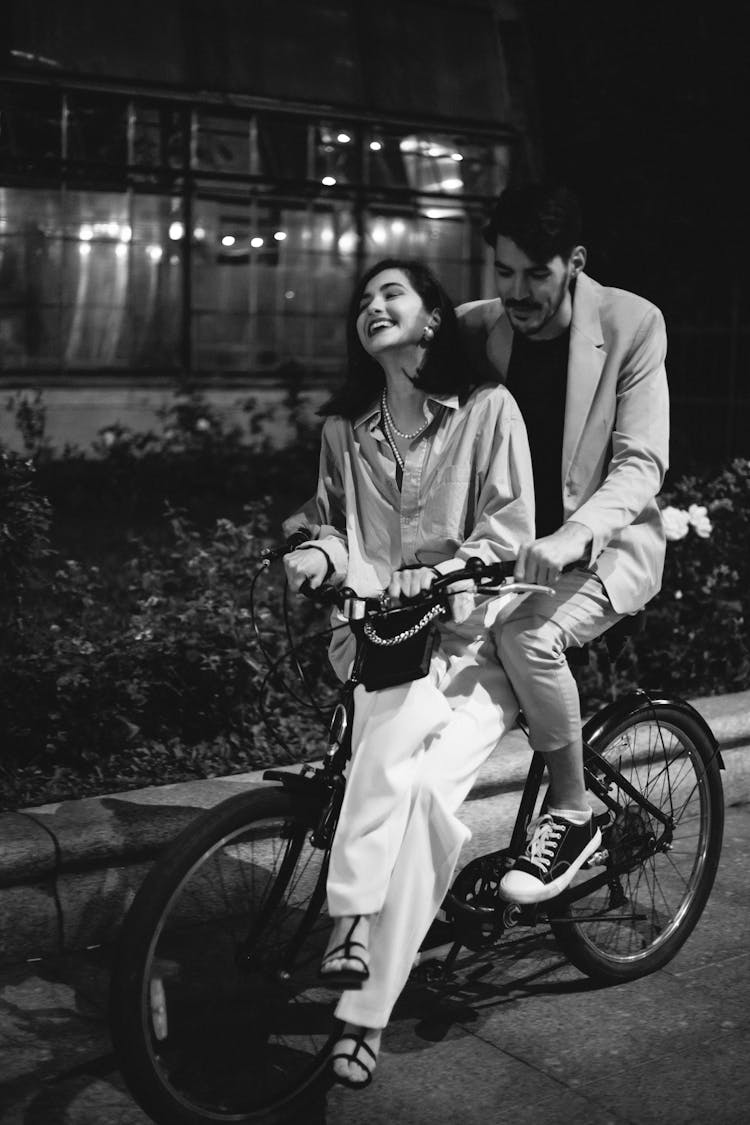 Black And White Photo Of A Couple Riding A Bike