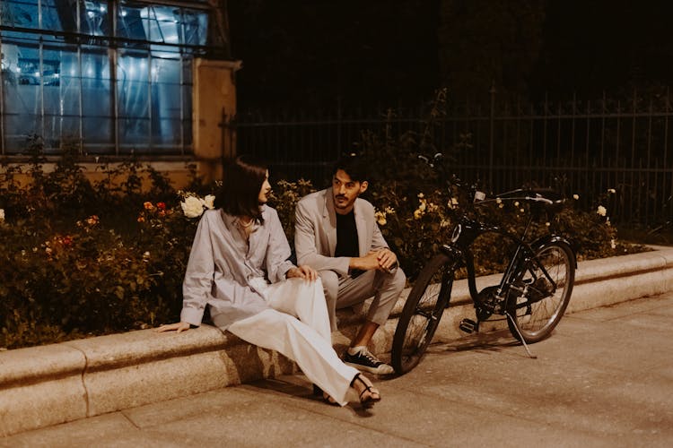 Woman And Man Sitting On Wall At Night