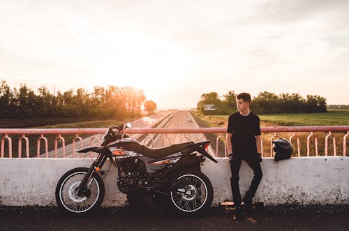 Free Photo of a Man in Black Clothes Sitting Near His Dirt Bike Stock Photo