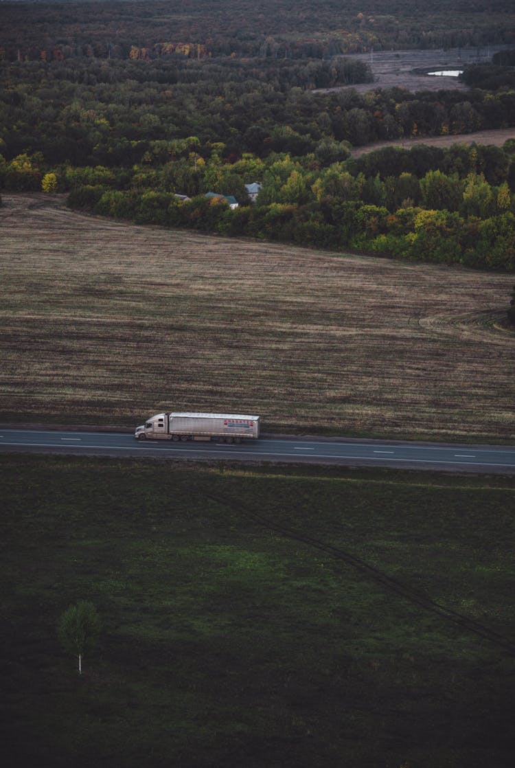 Aerial View Of A Truck Driving On A Road Between Fields 