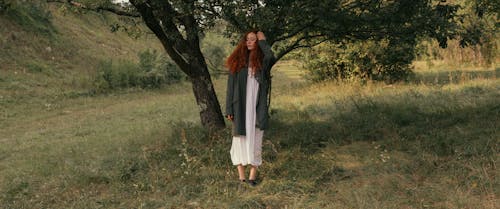 A Woman in White Dress Standing on Green Grass Field