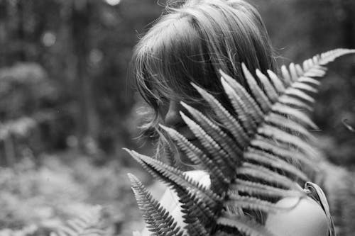 Monochrome Photo of a Woman Holding Fern Leaves